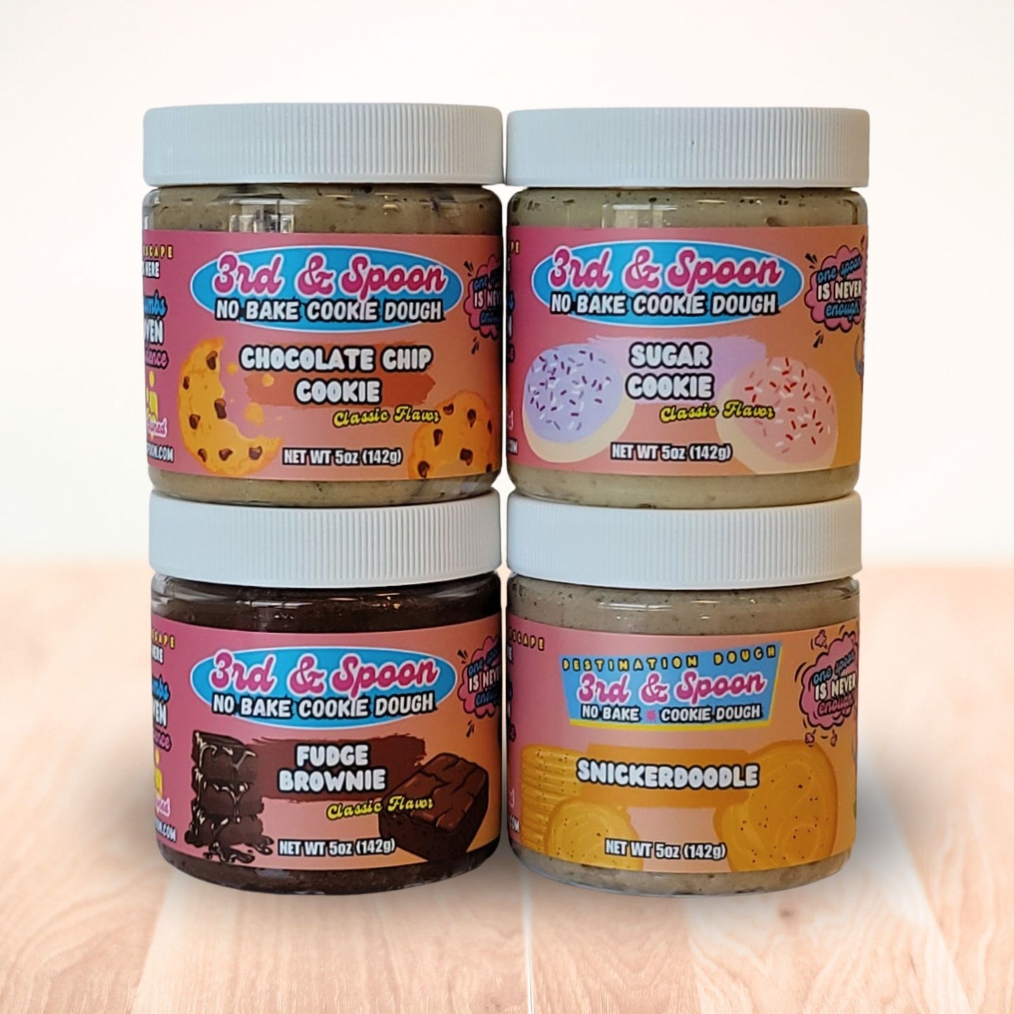 Four small jars of 3rd & Spoon edible cookie dough with different flavors on a light background.