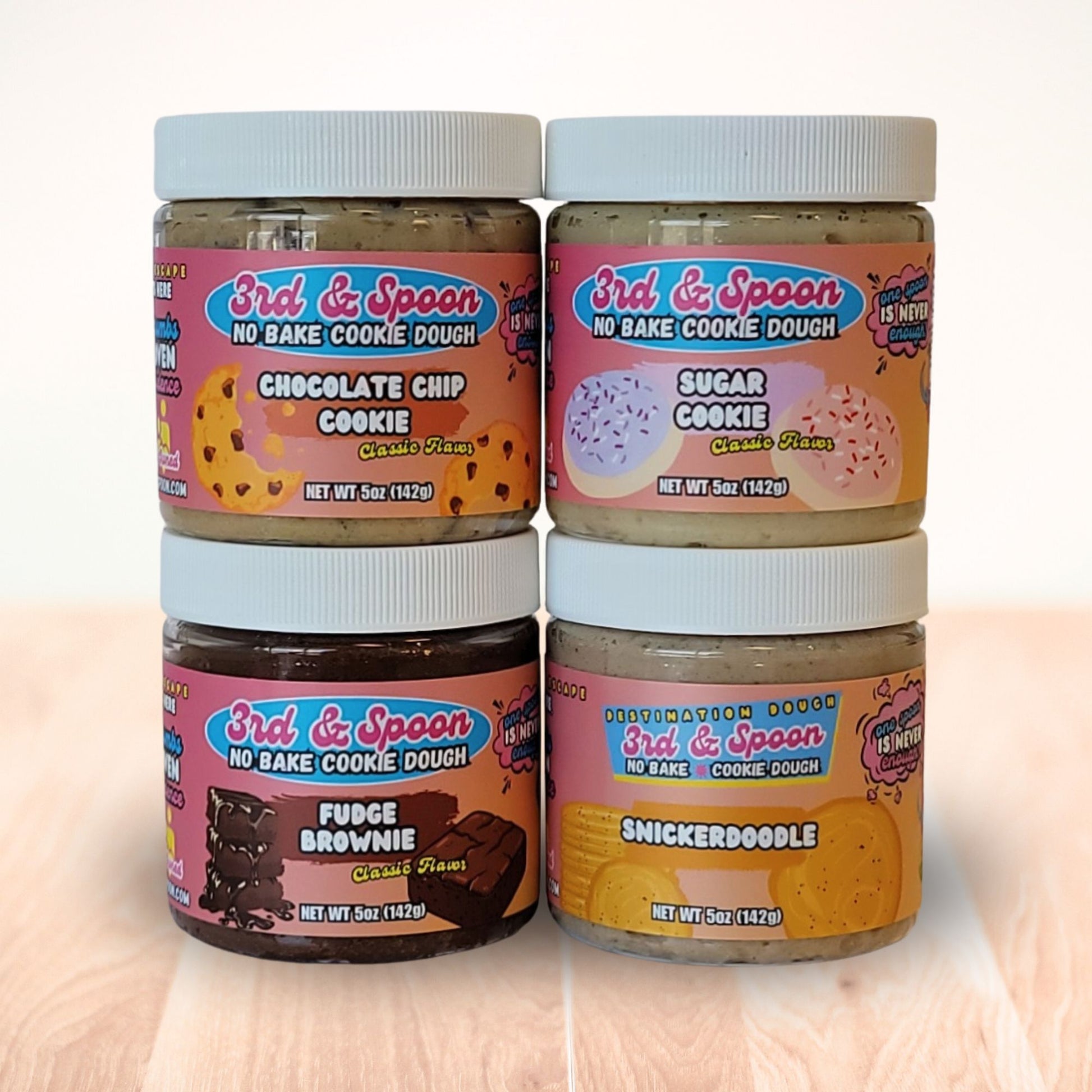 Four small jars of 3rd & Spoon edible cookie dough with different flavors on a light background.
