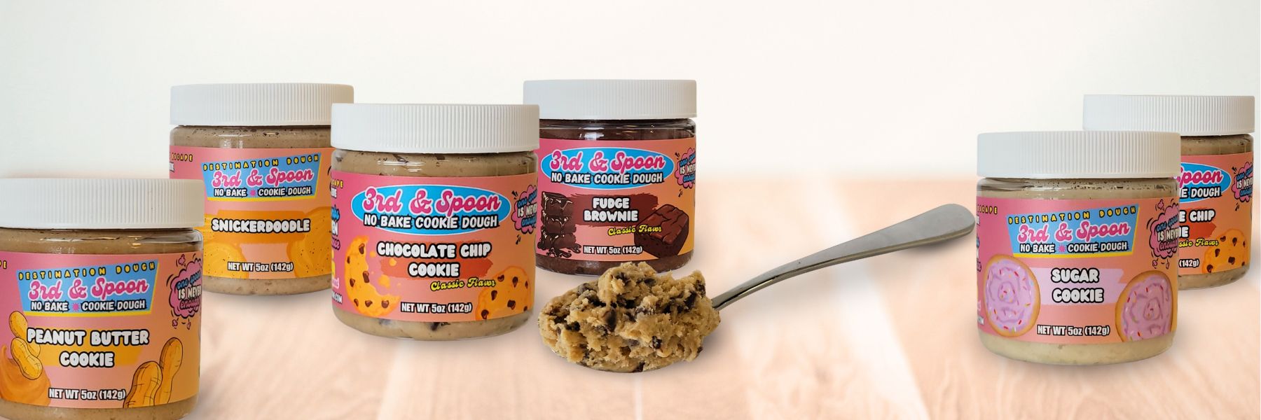 3rd & Spoon edible cookie dough jars with chocolate chip scoop and assorted flavors on display