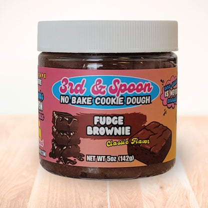5 oz jar of 3rd & Spoon fudge brownie edible cookie dough on a light wooden counter