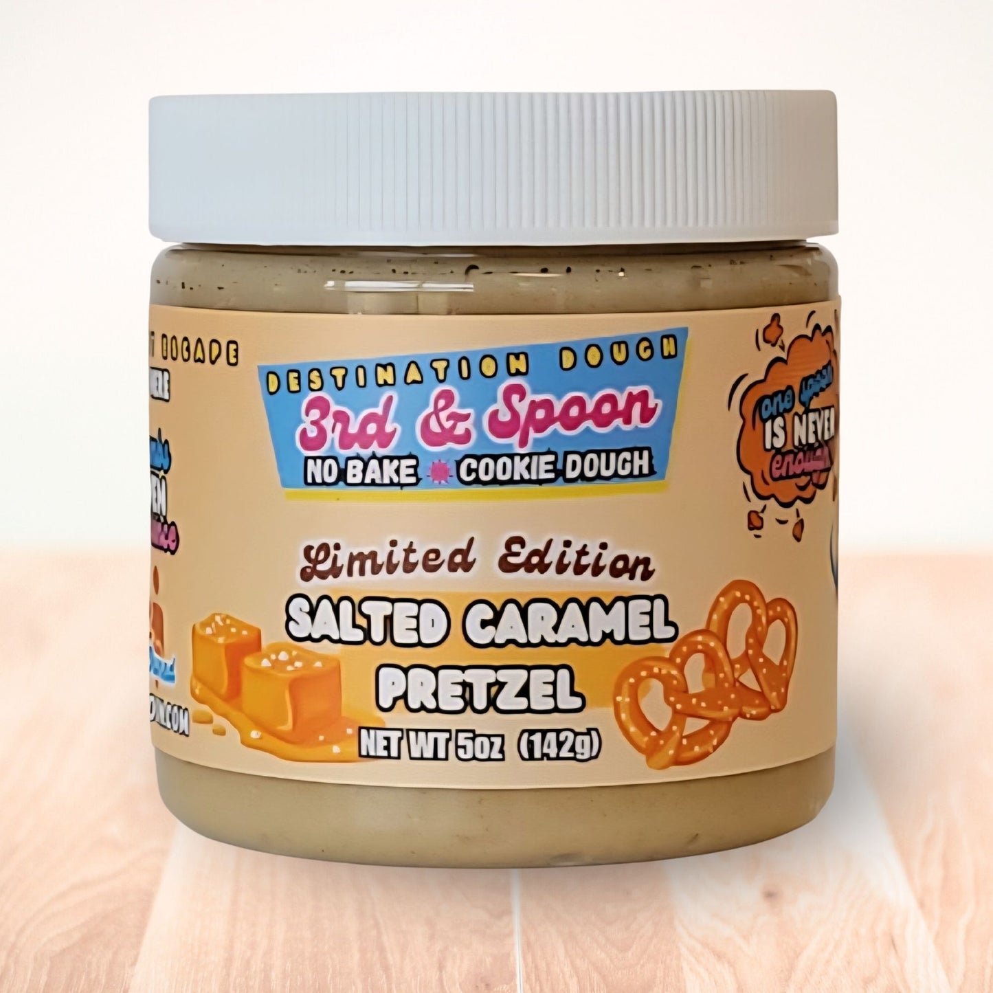 5 oz jar of 3rd & Spoon salted caramel pretzel edible cookie dough on a light wooden counter